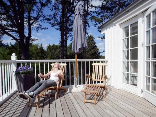 uma mulher sentada numa cadeira num deque com um guarda-chuva em 8 person holiday home in Nyk bing Sj em Rørvig
