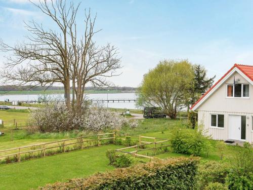 a white house with a fence next to a body of water at 8 person holiday home in Gelting in Gelting