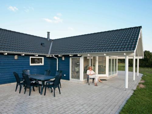 a woman sitting on the patio of a house at 10 person holiday home in R dby in Kramnitse