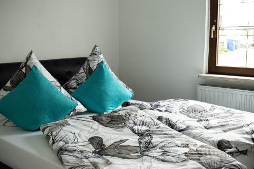ein Bett mit zwei blauen Kissen darauf in der Unterkunft Ferienwohnung Am Schlosspark in Ebersdorf
