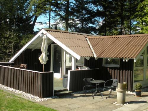 ein Haus mit einem Regenschirm, einem Tisch und Stühlen in der Unterkunft 4 person holiday home in Jerup in Jerup