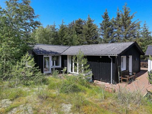 una casa negra en un campo con árboles en 6 person holiday home in lb k en Ålbæk