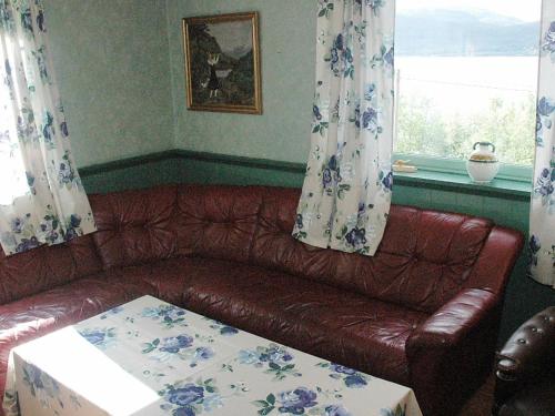 a brown leather couch in a living room with a window at Four-Bedroom Holiday home in Åfarnes in Årset