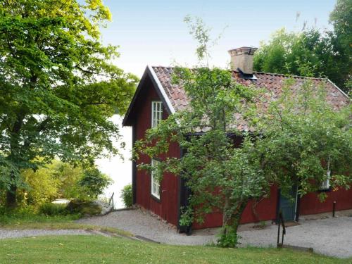 uma casa vermelha com uma árvore em frente em 5 person holiday home in MARIEFRED em Mariefred