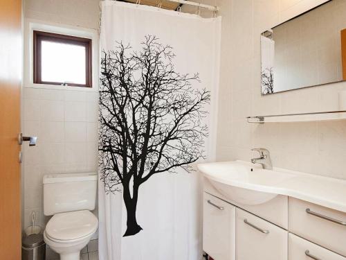 a bathroom with a tree stencil on the shower curtain at Holiday Home Lyngvejen VI in Rømø Kirkeby