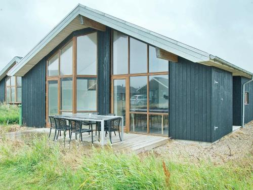 een houten terras met een tafel en stoelen voor een gebouw bij 8 person holiday home in Ulfborg in Thorsminde