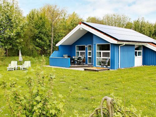 ein blaues Haus auf einem Feld mit einer Terrasse in der Unterkunft 6 person holiday home in Otterndorf in Otterndorf