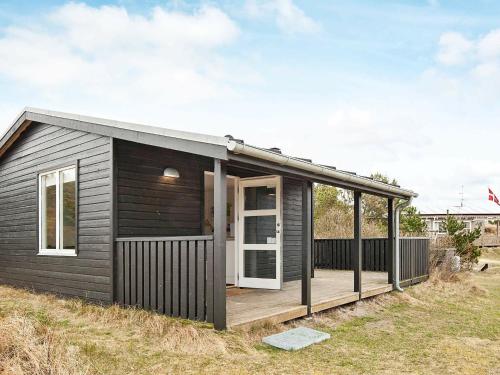 a small black house with a wooden deck at Lovely Holiday Home with Terrace in Vejers Strand in Vejers Strand