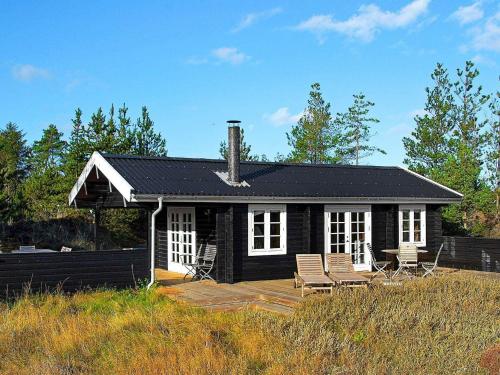 une petite maison noire avec une terrasse et des chaises dans l'établissement 6 person holiday home in lb k, à Ålbæk