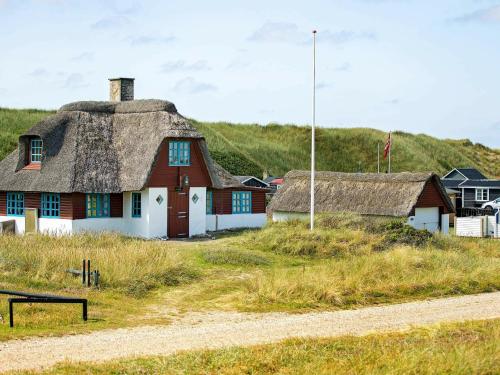 a house with a thatched roof next to a road at 5 person holiday home in Ulfborg in Fjand Gårde