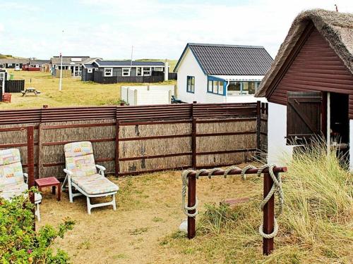 a wooden fence with two chairs in a yard at 5 person holiday home in Ulfborg in Fjand Gårde