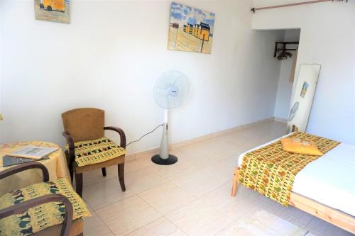 a room with a bed and a chair and a fan at B & B Villa Calliandra in Bijilo