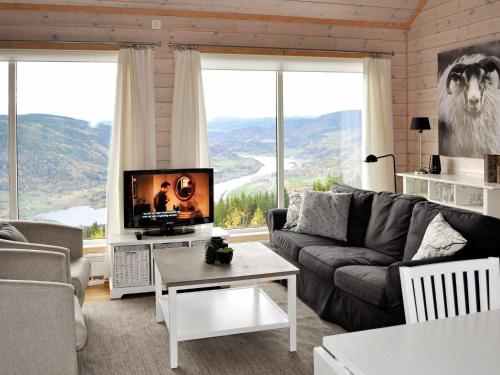 a living room with a couch and a television with mountains at Holiday home Øyer in Hafjell