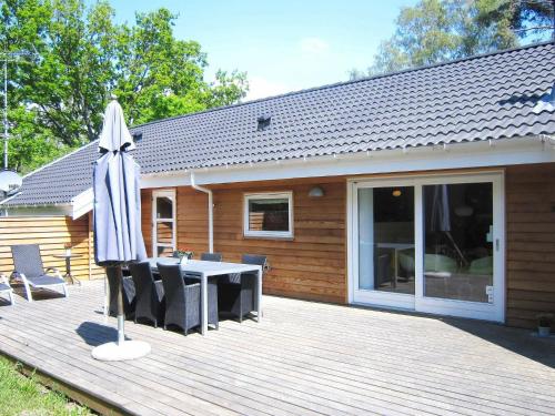 Vester Sømarkenにある10 person holiday home in Aakirkebyの木製デッキ(テーブル、傘付)