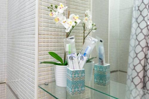 two vases with toothbrushes and flowers on a glass table at TGH Málaga centro histórico - Calle Alamos in Málaga