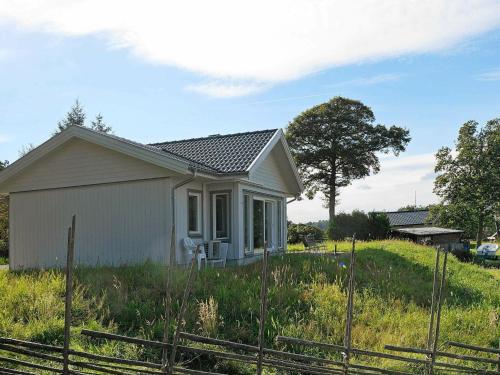 uma pequena casa branca num campo relvado em 5 person holiday home in LJUNGSKILE em Ljungskile