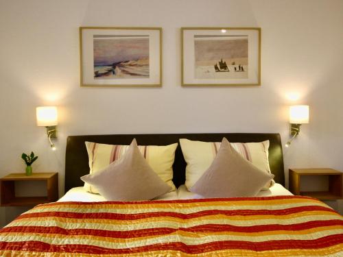 a bedroom with a bed with pillows and two pictures on the wall at Pension Kurhausblick in Bad Suderode