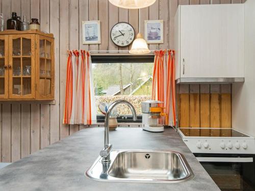 una cucina con lavandino e orologio sul muro di Three-Bedroom Holiday home in Toftlund 27 ad Arrild