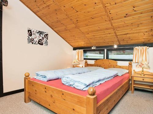 ArrildにあるThree-Bedroom Holiday home in Toftlund 27の木製の天井の客室のベッド1台分です。