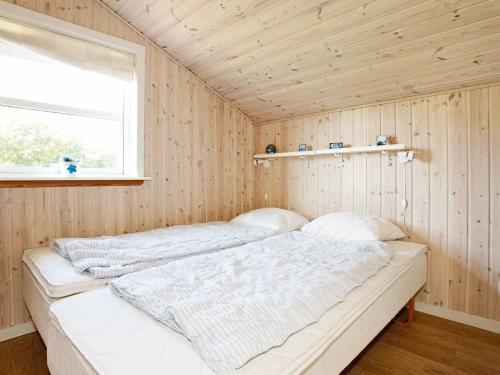 VestervigにあるThree-Bedroom Holiday home in Vestervig 1の窓のある木製の壁のドミトリールームのベッド1台分です。