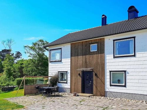 uma casa branca com uma porta de madeira e um pátio em 4 person holiday home in H LLEVIKSSTRAND em Hälleviksstrand