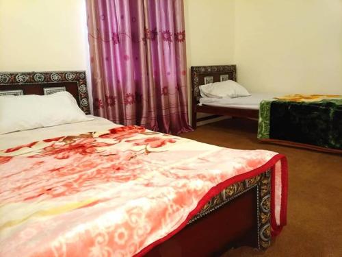 a bedroom with two beds with curtains and avertisement at Guest House De Grand Imperial in Hunza