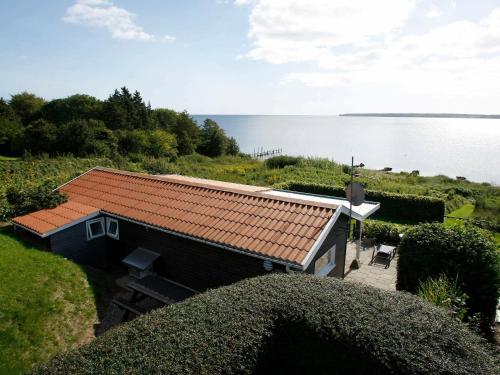 a small house with a red roof next to the water at 4 person holiday home in Juelsminde in Sønderby