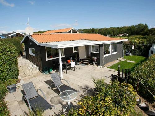 4 person holiday home in Juelsminde في Sønderby: منزل صغير مع كراسي وفناء