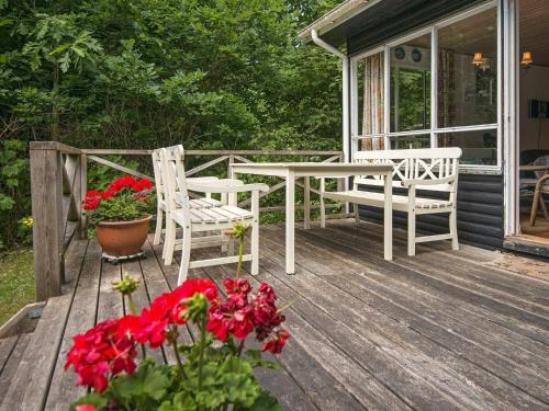 - une terrasse couverte avec une table, des chaises et des fleurs rouges dans l'établissement 4 person holiday home in Silkeborg, à Silkeborg