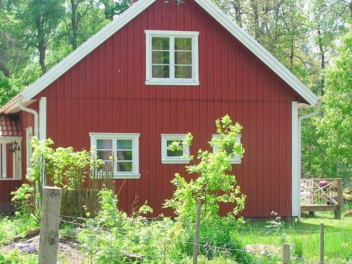 a red barn with white windows and a fence at 6 person holiday home in H CKSVIK in Håcksvik
