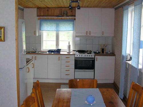 a kitchen with white cabinets and a table and a stove at 6 person holiday home in H CKSVIK in Håcksvik