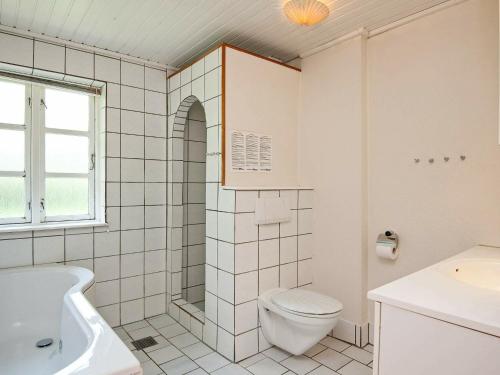 een witte badkamer met een toilet en een wastafel bij Holiday Home Møllebækvej in Nordborg