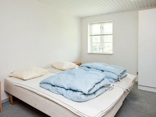een witte kamer met een bed met blauwe dekens bij Holiday Home Møllebækvej in Nordborg