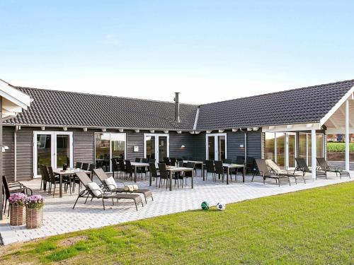 eine Terrasse mit Stühlen und Tischen auf einem Haus in der Unterkunft 30 person holiday home in Bogense in Bogense