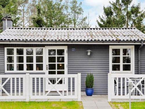 a small grey house with a white fence at 5 person holiday home in Ans By in Roe