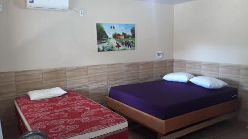um quarto com 2 camas individuais e um colchão vermelho em Pousada Aruanã em Soure