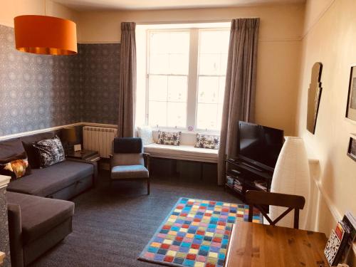 a living room with a couch and a tv and a window at Edinburgh Old Town Apartment in Edinburgh