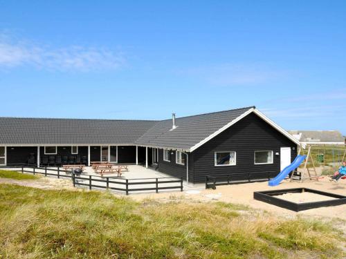 a black house with a playground and a slide at 22 person holiday home in Harbo re in Harboør