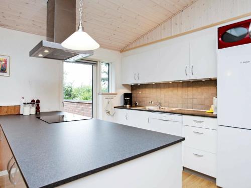 a kitchen with white cabinets and a black counter top at 6 person holiday home in Jerup in Jerup