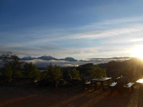 a sunset on a hill with a table and benches at Agriturismo La Casa Nei Boschi in Colderù