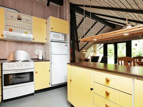 una cocina con electrodomésticos blancos y armarios amarillos en 4 person holiday home in R dby, en Kramnitse