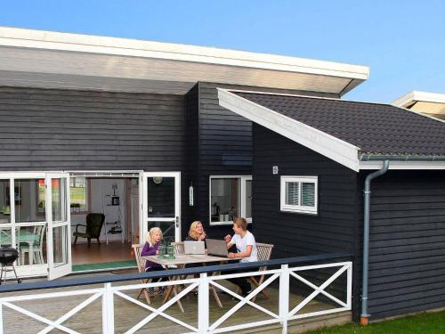 dos mujeres sentadas en la cubierta de una casa negra en 4 person holiday home in Gudhjem, en Gudhjem