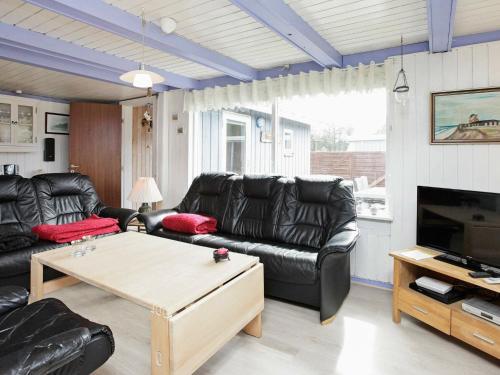 een woonkamer met een zwarte leren bank en een tafel bij 6 person holiday home in L kken in Løkken
