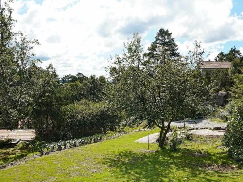 a garden with a tree and a stone wall at 4 person holiday home in H viksn s in Höviksnäs