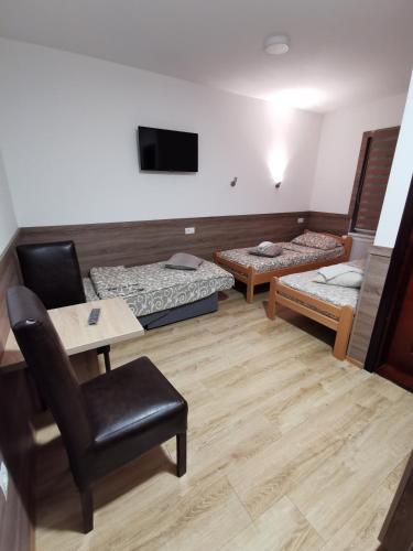 a room with two beds and a table and a chair at Vila Zlatarka in Nova Varoš