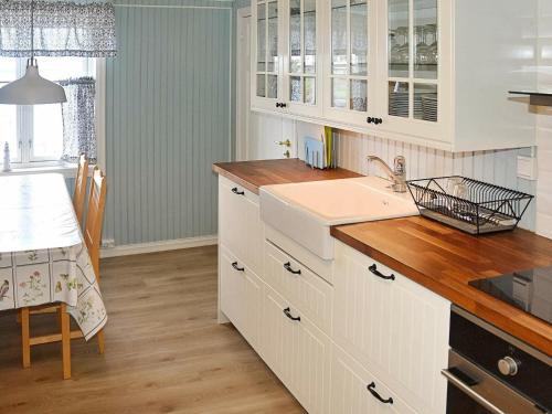 a kitchen with white cabinets and a wooden floor at 8 person holiday home in averøy in Henda