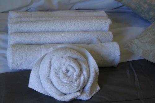 a stack of white towels on a bed at Duca's Guest House in Turin