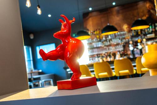 a red statue sitting on top of a counter in a bar at ibis Styles Douai Gare Gayant Expo in Douai