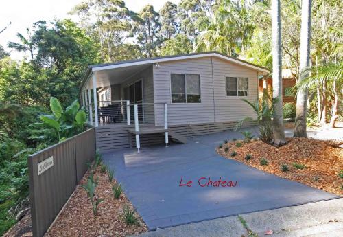 a tiny house with a porch and a driveway at The Palms At Avoca in Avoca Beach