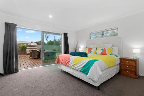 a bedroom with a bed and a balcony with a table at Kihi Retreat - Ruakaka Holiday Home in Ruakaka